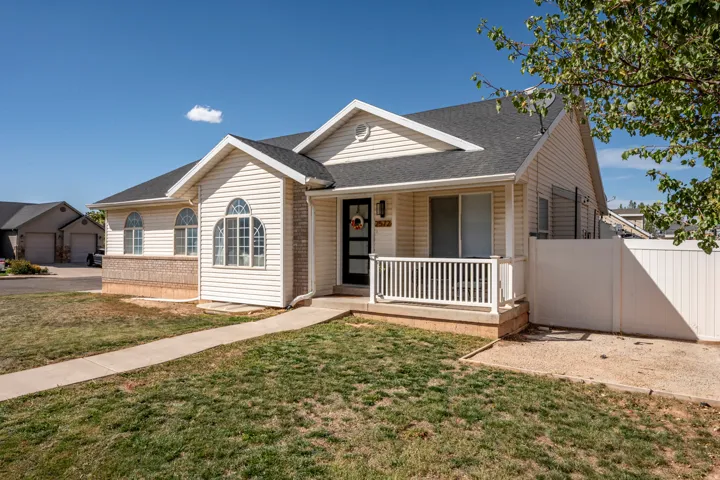 Cream siding exterior featuring a covered front porch, arched windows, and a privacy fence