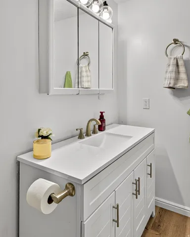 White vanity with an integrated rectangular sink, bronze-finish faucet, and coordinating cabinet pulls