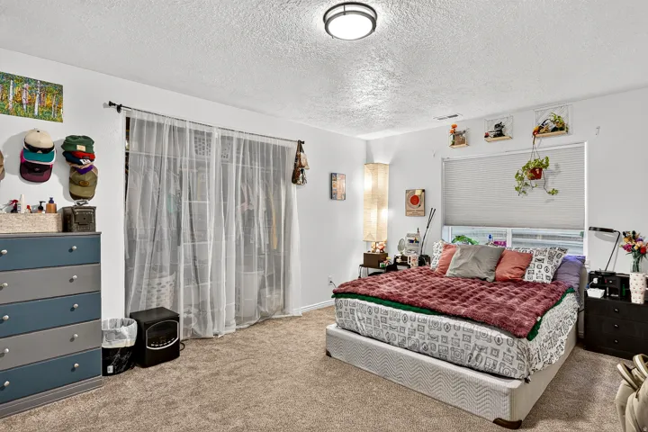 Neutral tone walls with textured ceiling and carpeted flooring