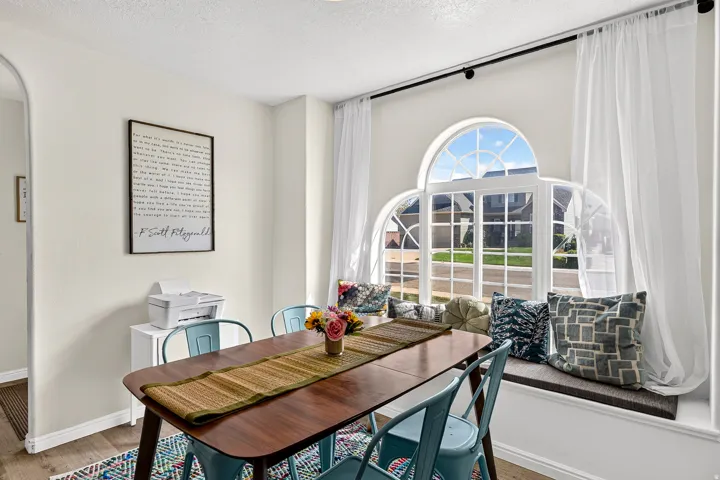 Arched window with gridded panes, built-in window seat, wood-finish flooring, and a cased opening