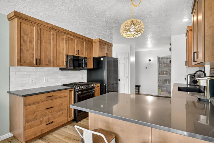 Kitchen featuring wood-finish cabinetry, dark countertops, a tile backsplash, and stainless steel appliances