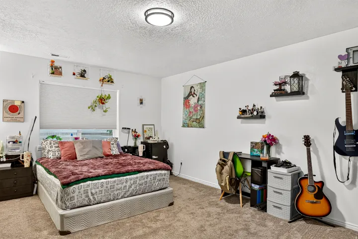 Carpeted flooring, white walls, and a single window with blinds