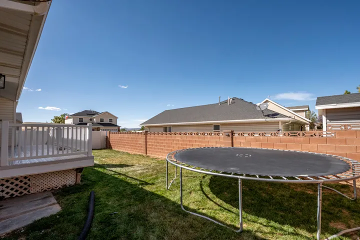 Expansive backyard featuring a manicured lawn, a privacy fence, and an elevated composite deck with white railings