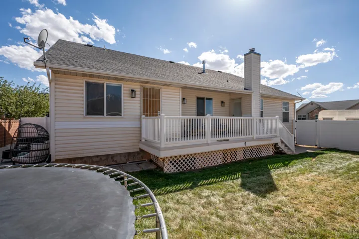 Expansive backyard featuring a manicured lawn, a full-width deck with white railing, and a privacy fence