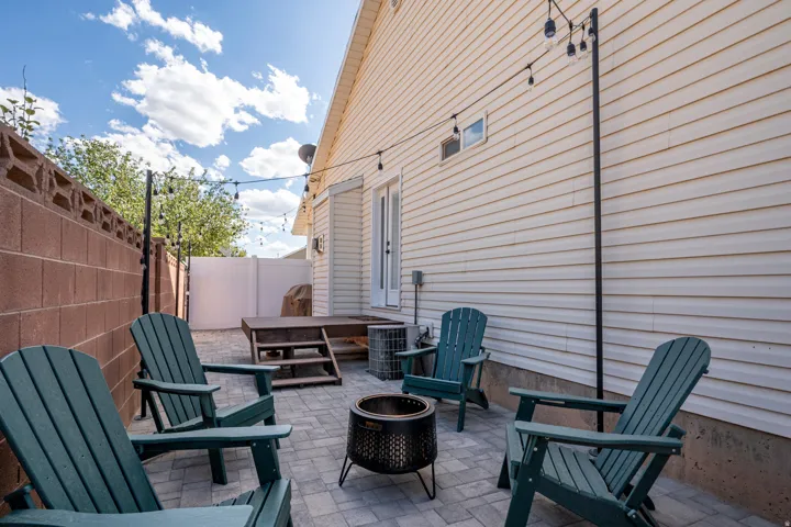 Paved patio area featuring string lighting, a raised wood deck, and a privacy fence