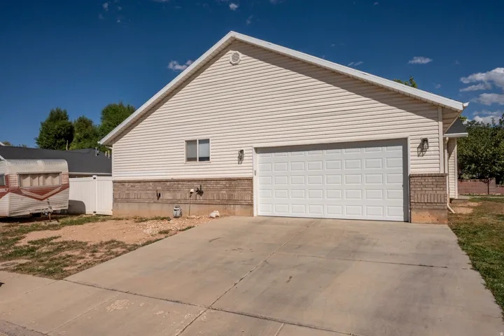 White paneled garage door, light-colored brick veneer, vinyl siding, and a concrete driveway