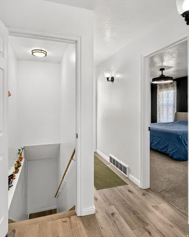 Wood-finish flooring, white painted walls, and a contemporary flush-mount ceiling light