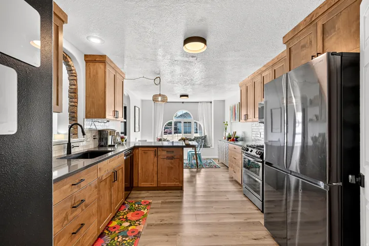 Kitchen featuring wood cabinetry, dark countertops, stainless steel appliances, and wood-finish flooring