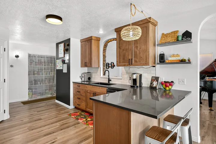 Kitchen featuring light wood-finish cabinetry, a black sink with a matte black faucet, and light countertops