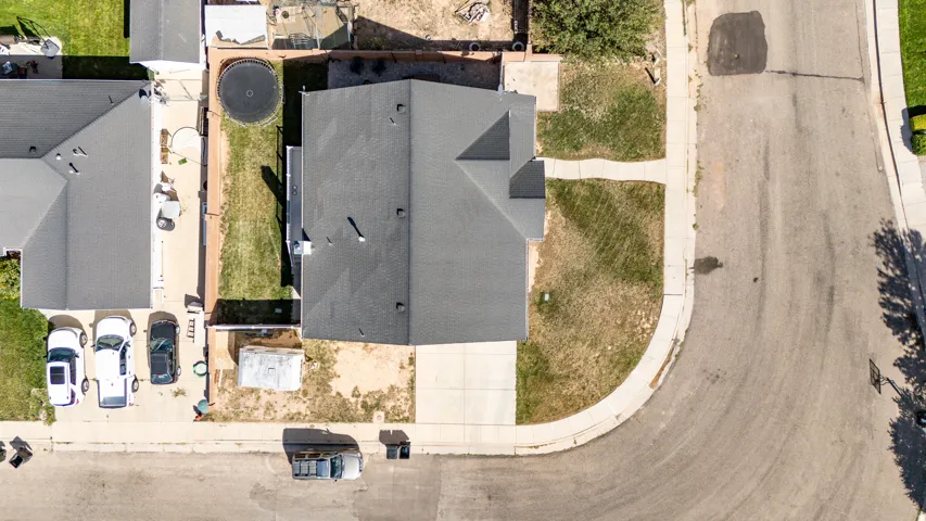 Asphalt shingle roof, paved driveway, concrete sidewalk, grassy front yard, and an adjacent street