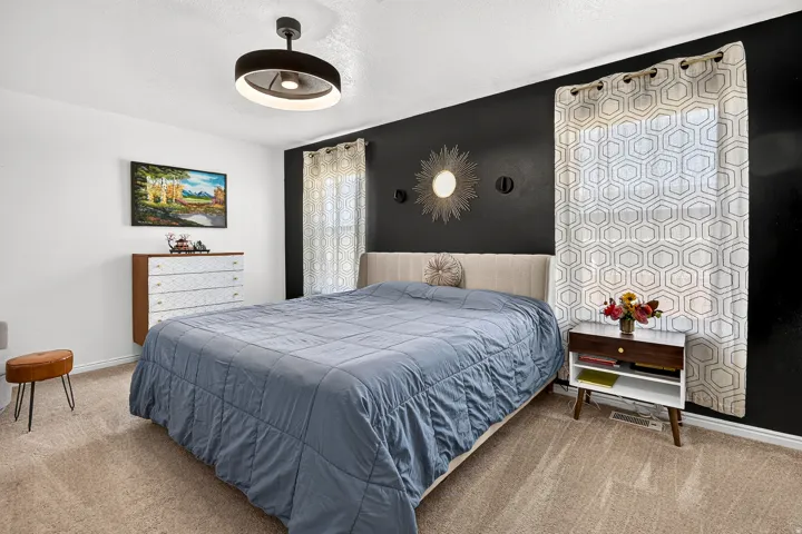 Plush carpet flooring, ceiling-mounted light fixture, and a feature wall