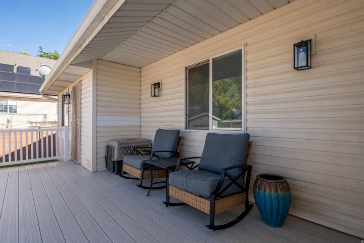 Covered outdoor deck with composite decking, white railing, and exterior wall lanterns
