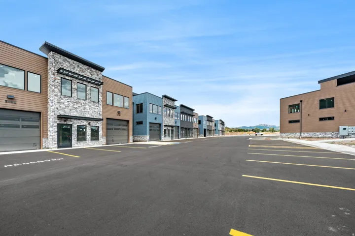 Modern commercial units with mixed-material facades, individual garage doors, and dedicated parking spaces