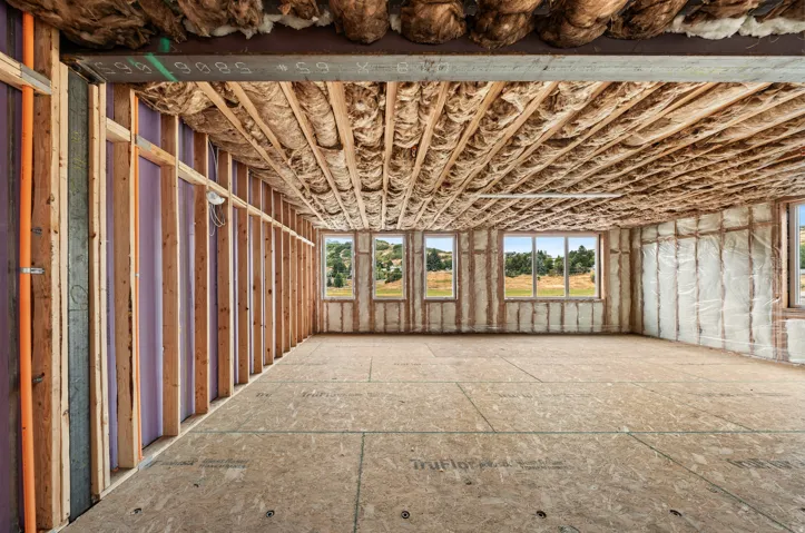 Unfinished interior space featuring wood framing, exposed insulation, and multiple windows