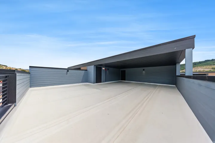 Expansive rooftop deck featuring a partial overhang, exterior siding, and a protective railing