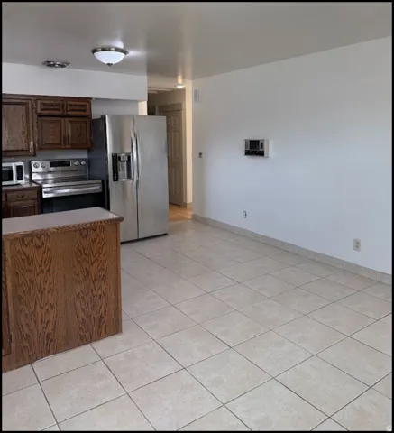 Kitchen area featuring wood cabinetry, stainless steel appliances, and tile flooring. Photo shown was taken prior to tenant occupancy and is provided for reference.