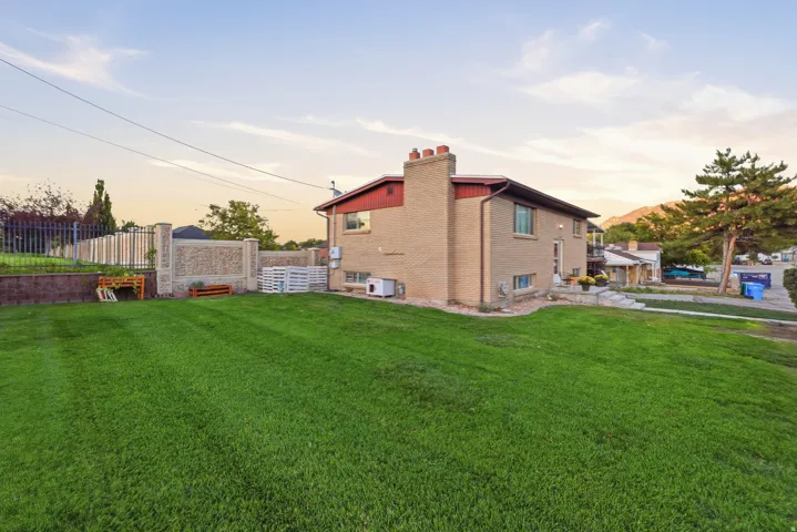 Expansive green lawn with a brick exterior, prominent chimney, and a multi-level fenced yard