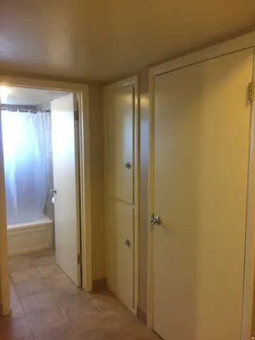 Built-in storage cabinetry, bathroom view with tiled flooring, tiled tub and shower. Photo shown was taken prior to tenant occupancy and is provided for reference.