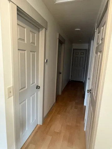 Wood-finish flooring throughout the hallway, smart thermostat, Photo shown was taken prior to tenant occupancy and is provided for reference.