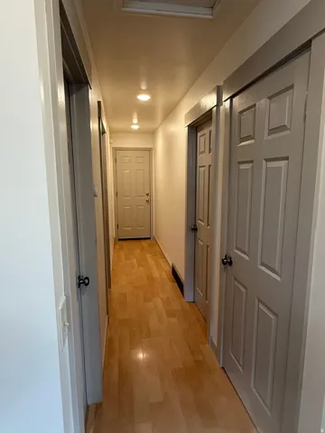 Hallway featuring wood-finish flooring, recessed lighting, and panel doors. Photo shown was taken prior to tenant occupancy and is provided for reference.