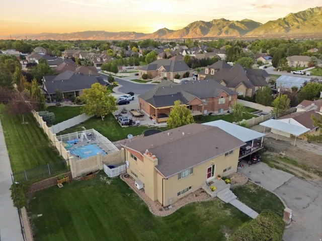 Expansive residential property featuring a side yard, mature landscaping, cement driveway, and covered carport