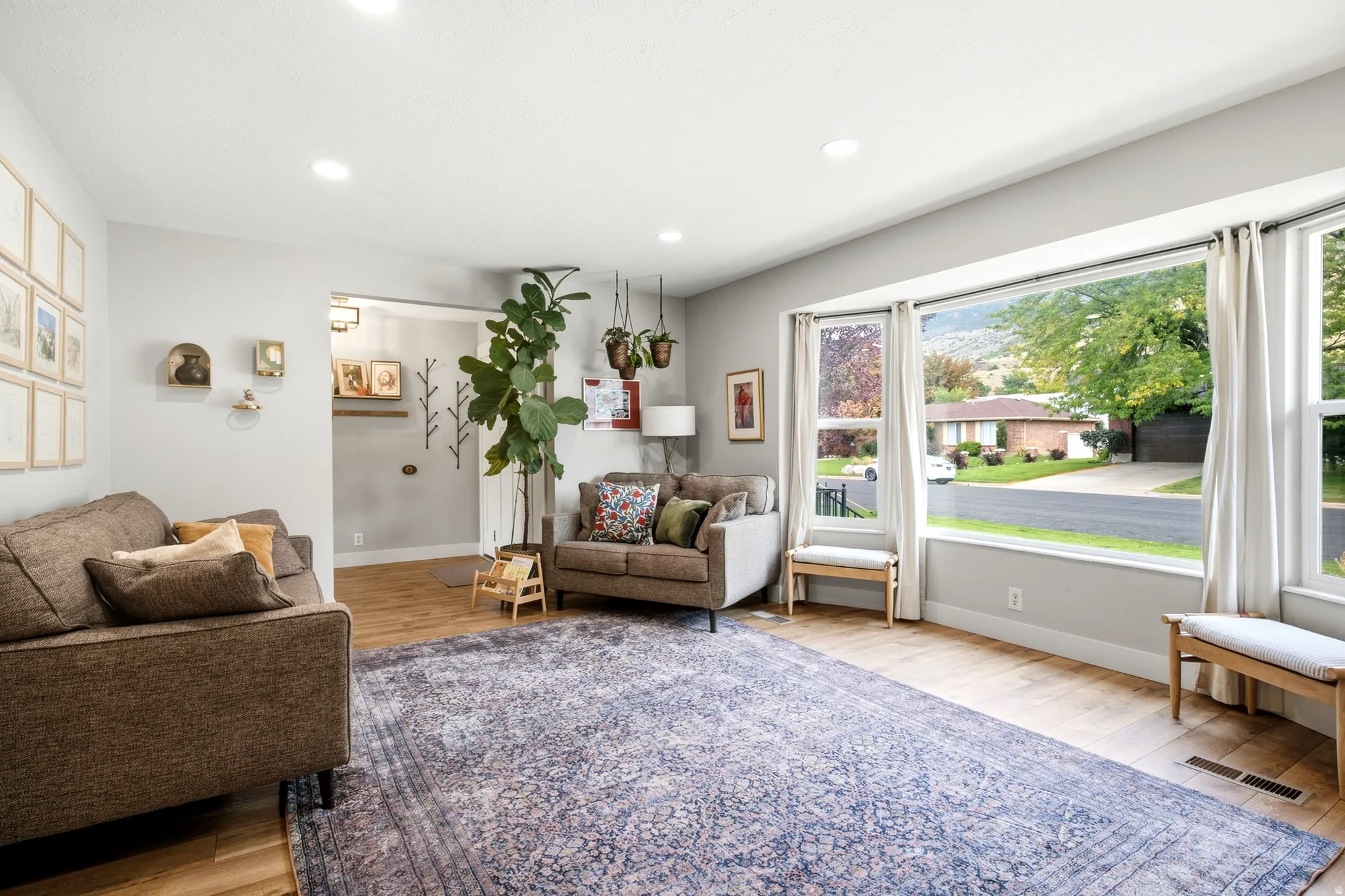 Spacious living area featuring wood-finish flooring, recessed lighting, and a large bay window