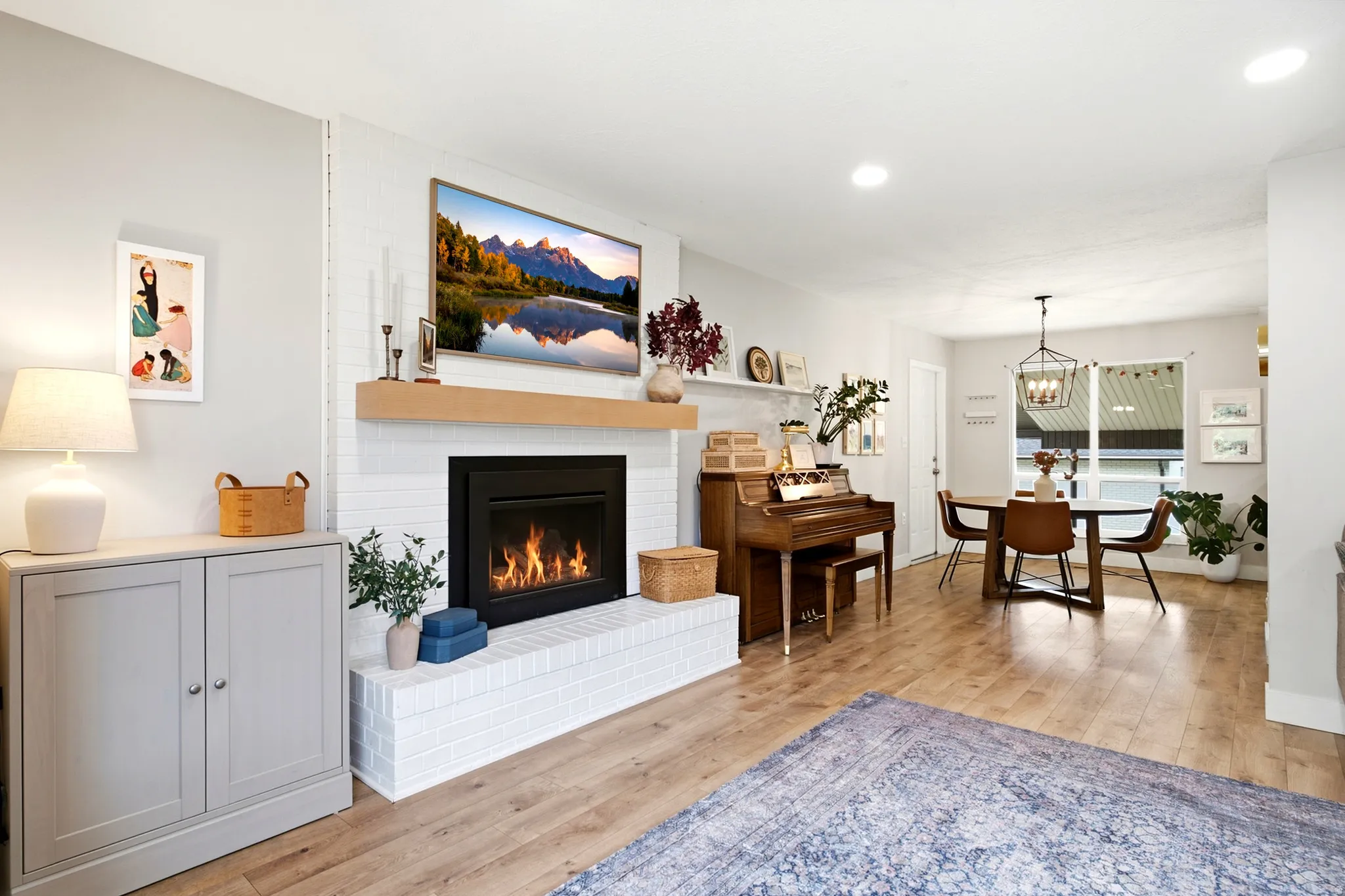 White brick fireplace with a wood mantel, recessed lighting, and wood-finish flooring