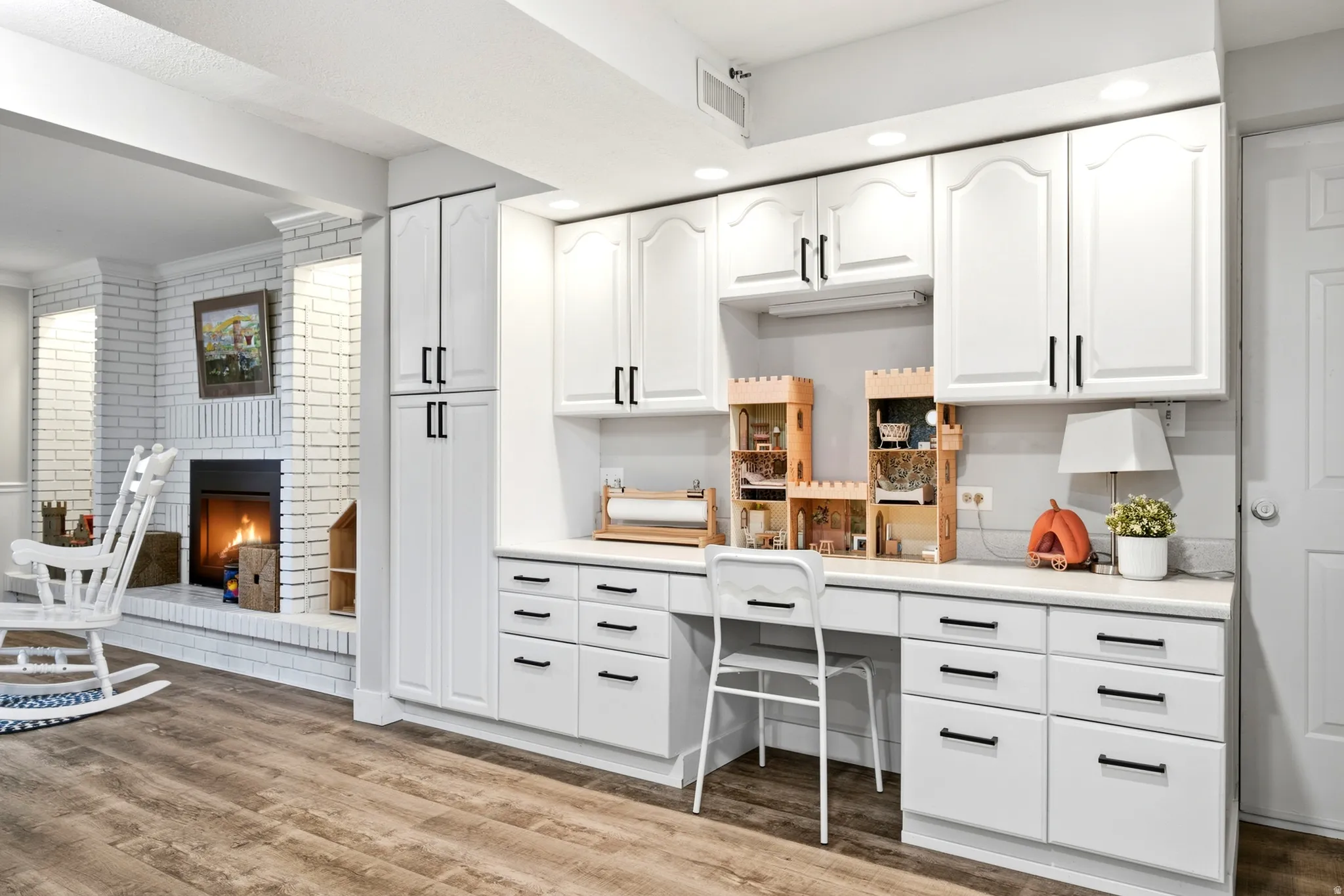 Custom built-in white cabinetry with black hardware, integrated desk, and undermount lighting