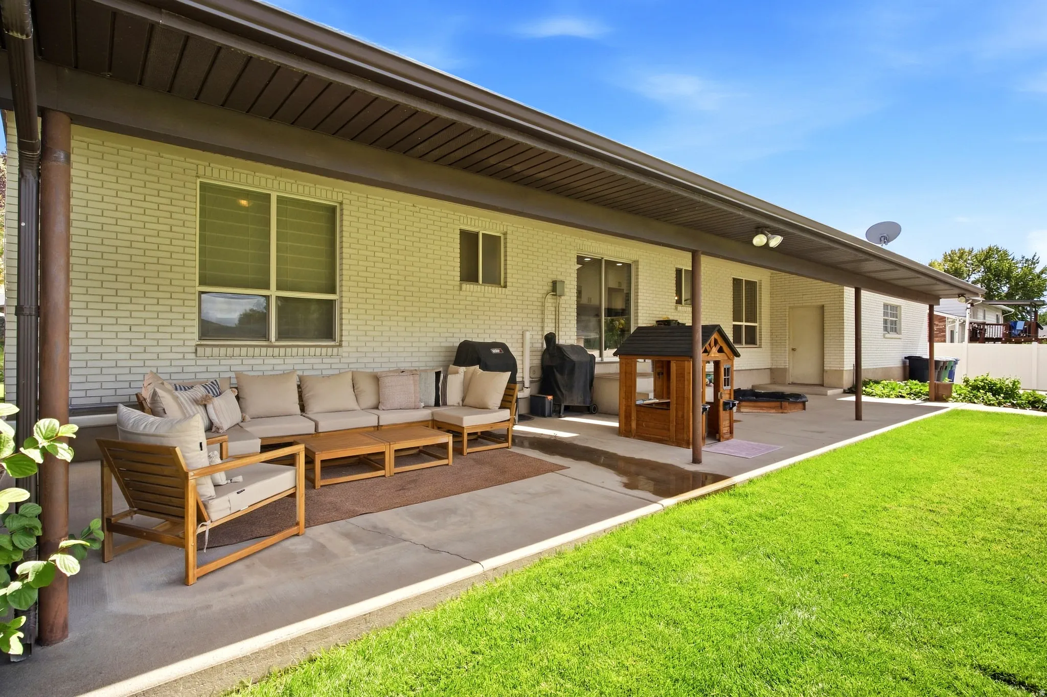 Covered concrete patio with recessed lighting and a white brick exterior