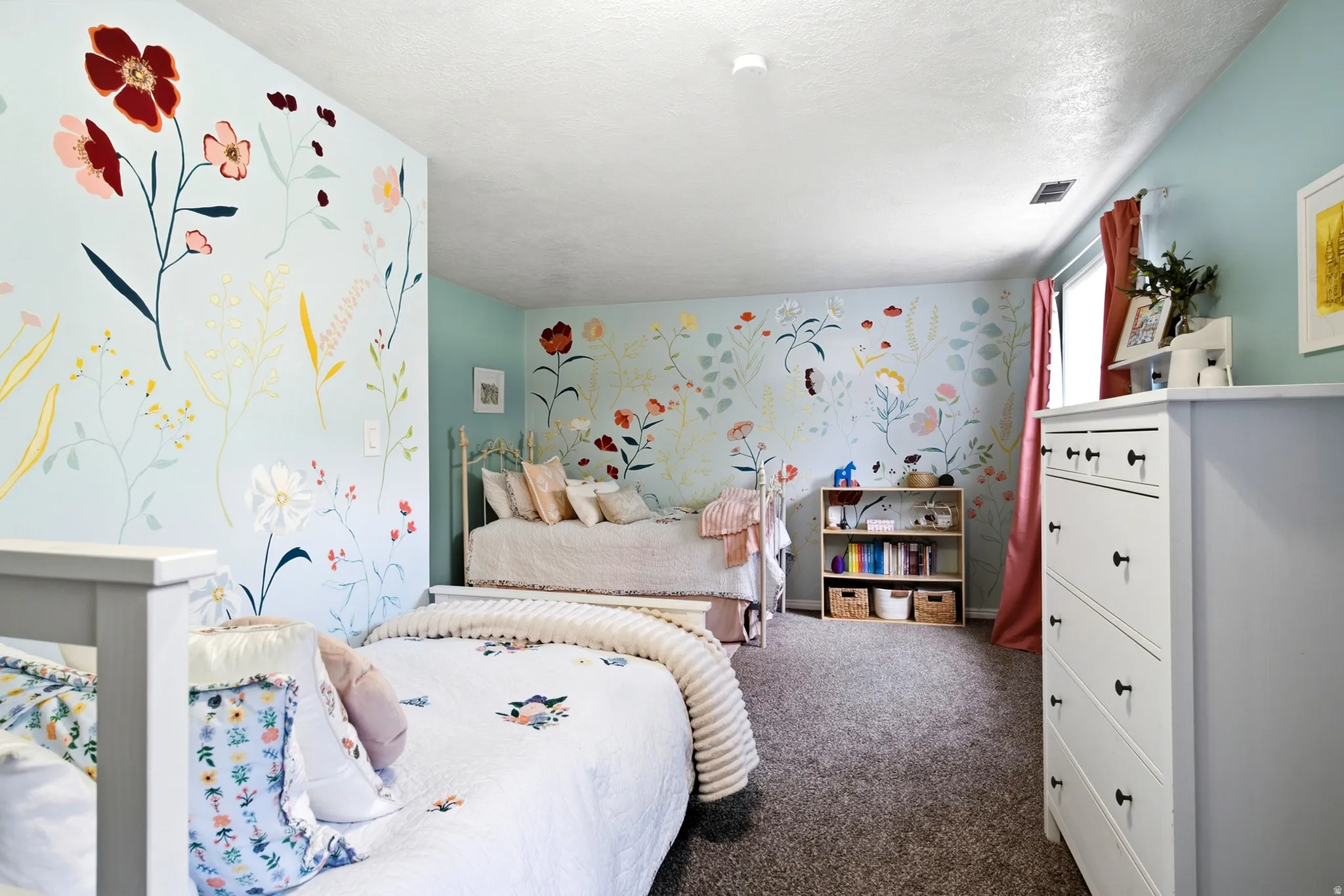 Wall-to-wall carpeting, light blue walls with floral patterns, and a built-in shelving unit