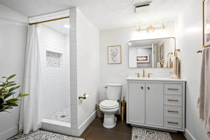 Walk-in shower with subway tile surround and pebble-finish floor