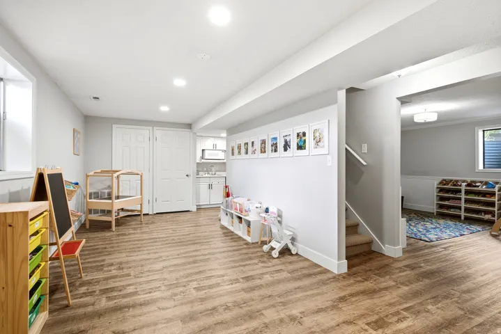 Recessed lighting, wood-finish flooring, white trim, and a built-in wet bar with white cabinetry and a microwave
