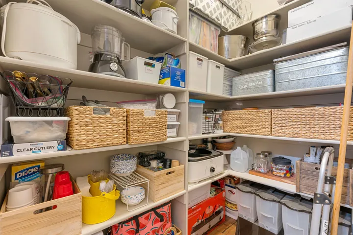 Corner pantry featuring multiple built-in shelving units providing extensive storage