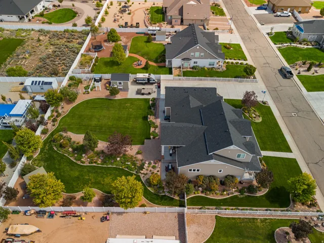 Expansive lawn with mature landscaping, white privacy fencing, and an adjacent gravel area