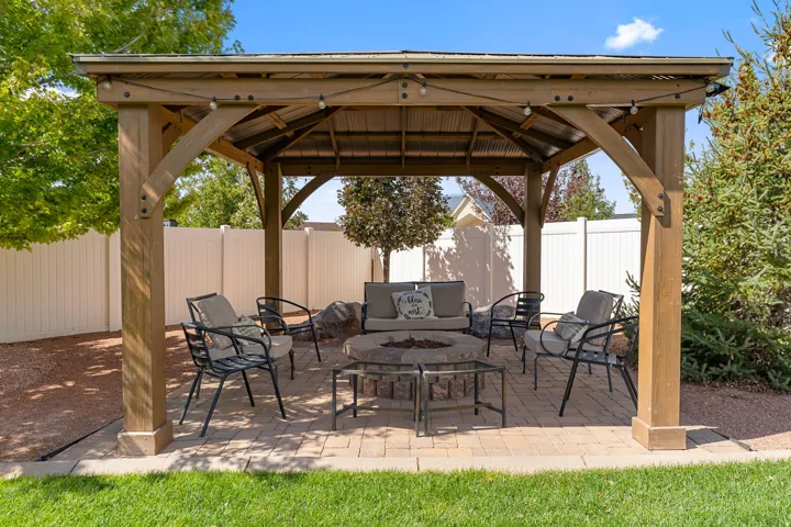 Wooden gazebo with a corrugated metal roof over a paver patio