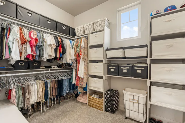 Walk-in closet featuring built-in shelving, multiple hanging rods, and a window for natural illumination