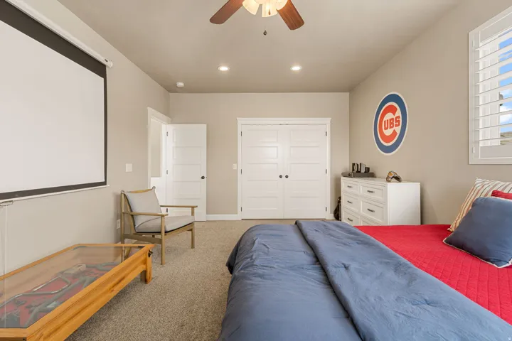 Built-in projection screen, ceiling fan, recessed lighting, white louvered window shutters, and plush carpet flooring