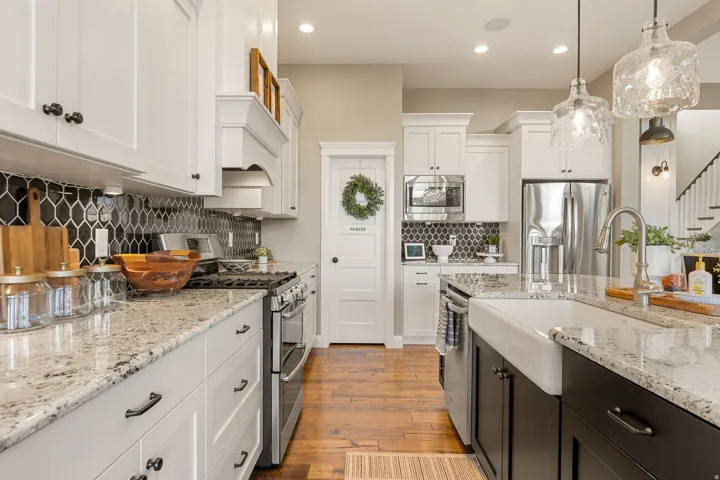Spacious kitchen with white shaker cabinetry, stainless steel appliances, granite countertops, and a full-height black hexagonal tile backsplash
