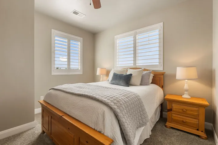 Two windows with white plantation shutters, neutral wall color, and carpeted flooring