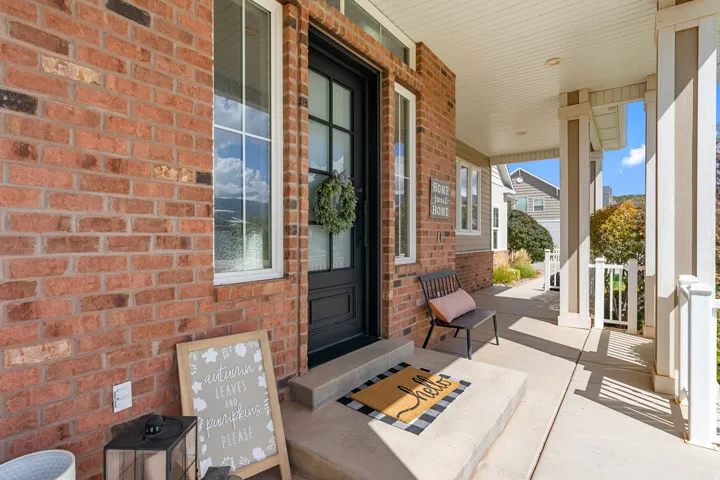 Brick exterior with white-framed windows, a black entry door, and a covered porch