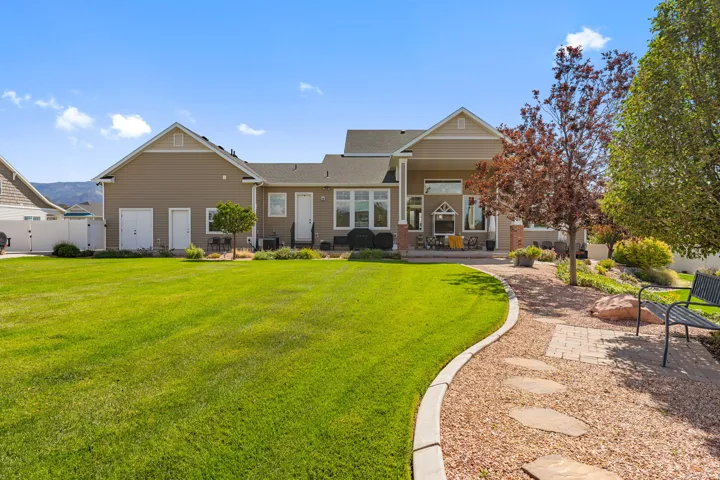 Expansive lawn with a stone-edged gravel pathway, mature trees, and a covered patio