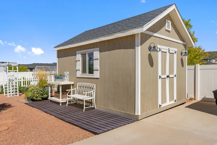 Shed structure with horizontal siding, a gabled roof, and a single window with white shutters