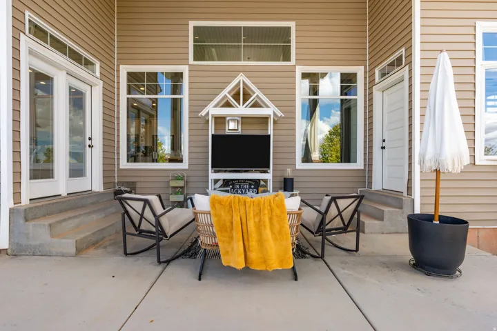 Patio area featuring concrete flooring, tan siding, and a white architectural accent over an entertainment alcove