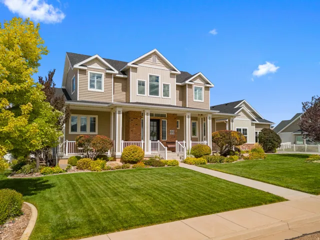 Two-story residence featuring a covered front porch, brick and siding exterior, multiple gables, and an attached garage
