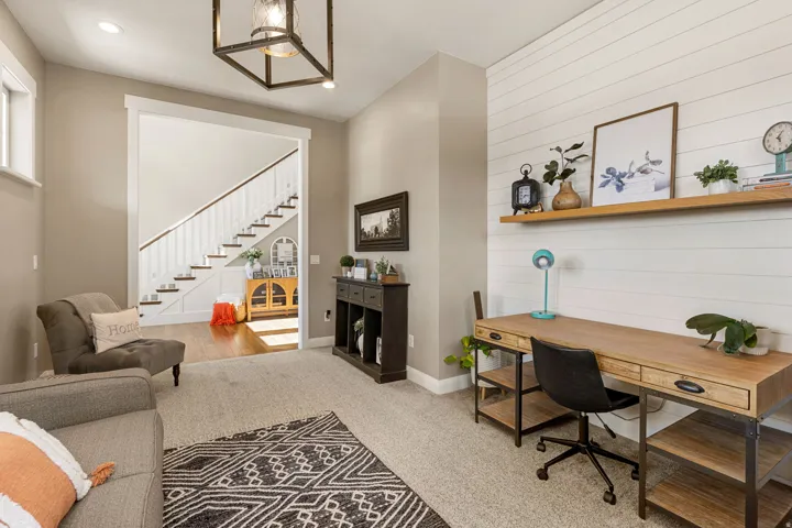 White shiplap wall accent, wood-finish desktop with metal frame, wood-finish floating shelf, recessed ceiling lighting, and a dark metal frame chandelier