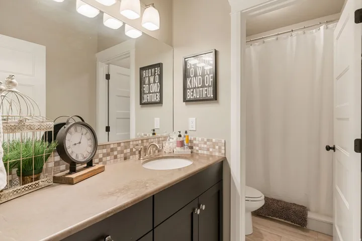 Vanity with a single basin, brushed nickel faucet, and multi-toned tile backsplash