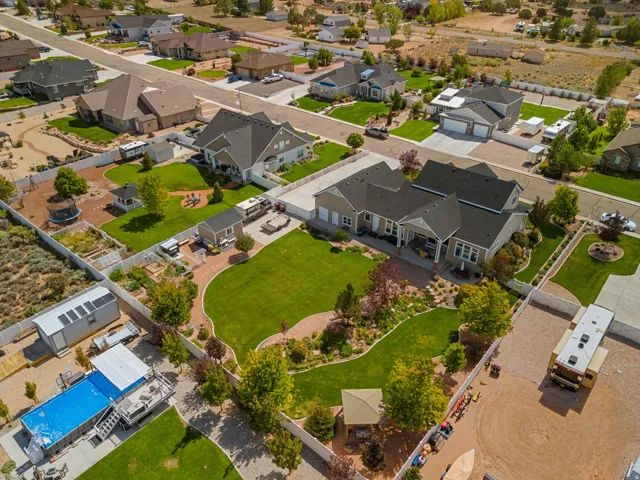 Expansive property featuring a vibrant green lawn, mature landscaping, paved driveway, detached auxiliary building, and a swimming pool
