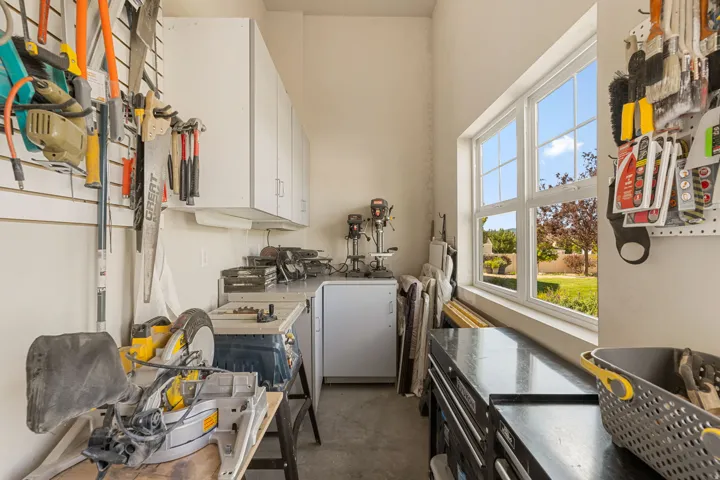 Integrated wall-mounted storage, built-in upper cabinetry, expansive work surfaces, window with outdoor scenery, and concrete flooring