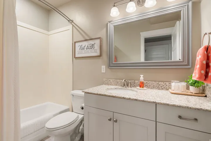Bathroom featuring a white vanity with panel-front cabinetry, a light-toned countertop, a rectangular undermount sink, and a framed mirror