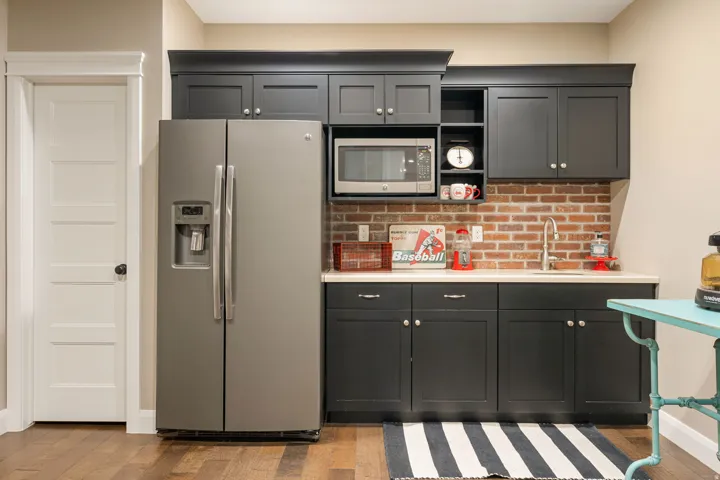 Built-in cabinetry with matte finish, brick backsplash, stainless steel sink, and wood-finish flooring
